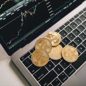 Bitcoin coins on a laptop keyboard, with a graph indicating crypto market trends, symbolizing the Voluntary Disclosure Programme for crypto traders